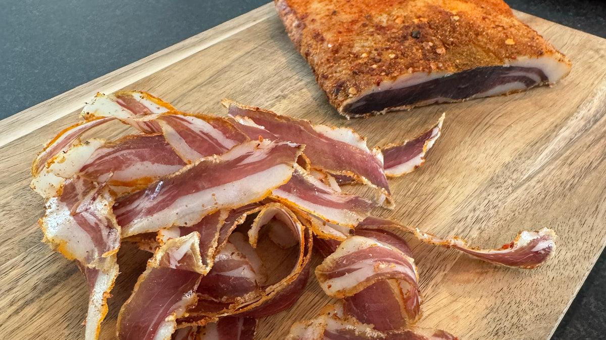 Sliced cured wild boar meat on a wooden cutting board