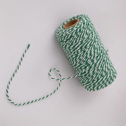 Roll of green and white striped butcher string, butcher twine, meat string, meat twine on a light gray background