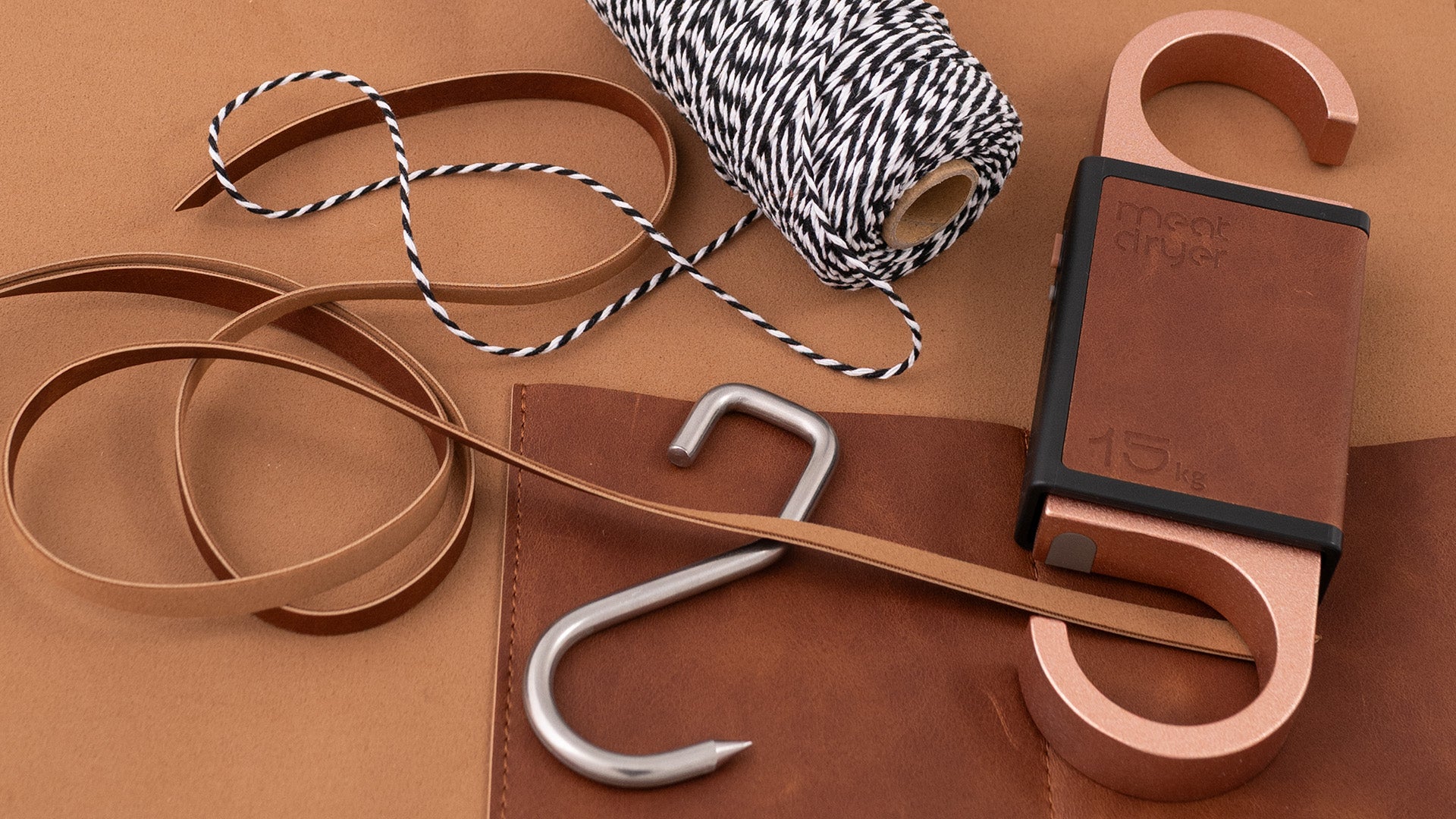 Brown tool bag with meat hook and bakers string on a brown background