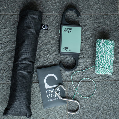 Meat drying equipment including a black insect net, string, and sharp metal meat hook on a stone surface